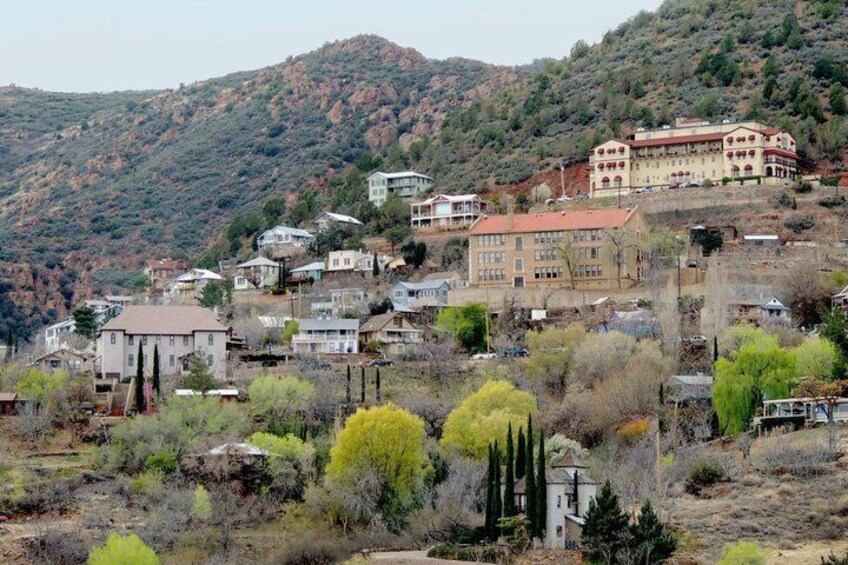 A hillside settlement with buildings, cypress trees, and a mountainous backdrop. 4