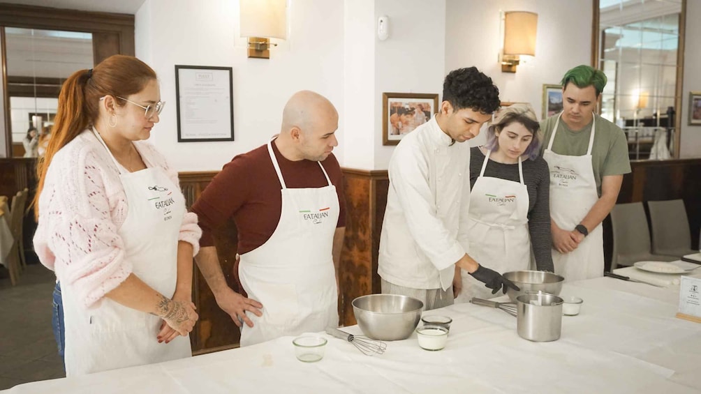 A group of people in aprons preparing food in a kitchen. 2