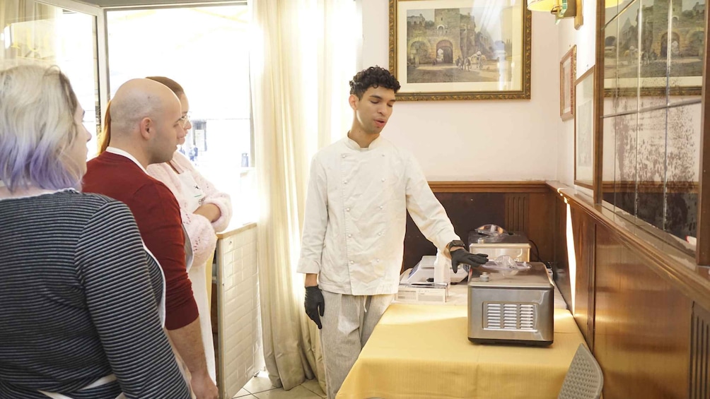 A chef in a white uniform standing by a table with a food display and a vintage radio. 5