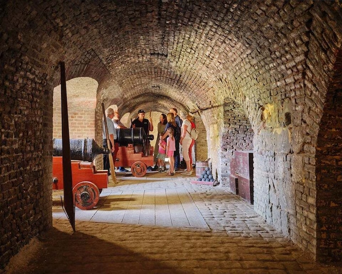 A stone tunnel with a group of people and a red cart. 1