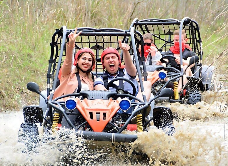 People in off-road vehicles driving through a muddy terrain. 2