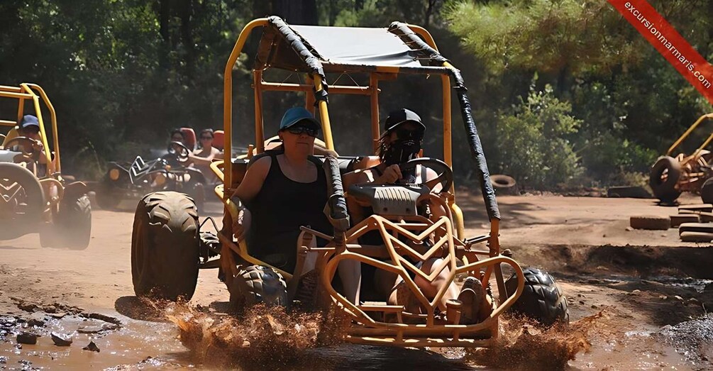 A person driving a yellow off-road vehicle through a muddy terrain with other similar vehicles in the background. 3