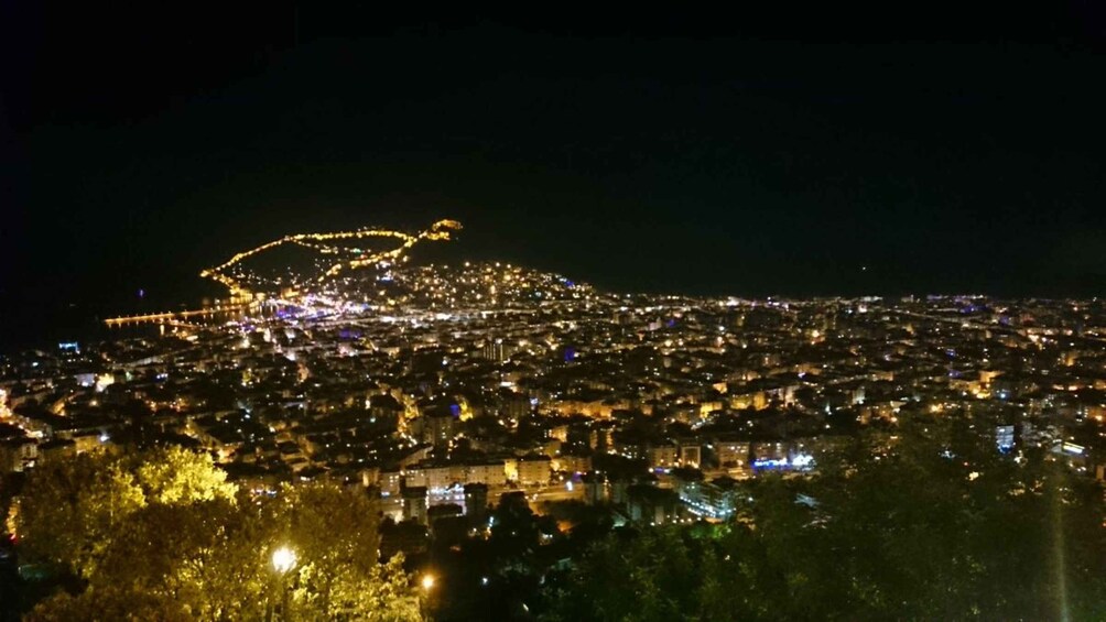 A nighttime cityscape with illuminated buildings and a prominent curved light display. 5