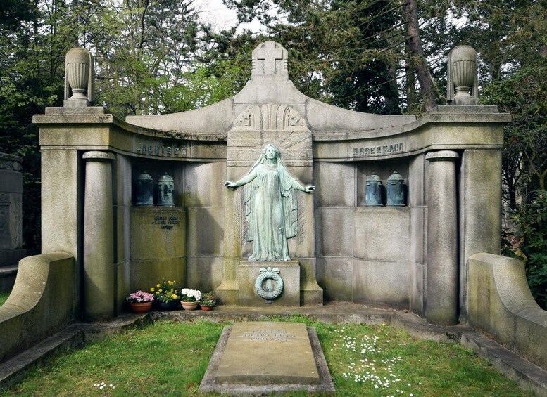 A stone monument with a statue of a woman, surrounded by trees. 4