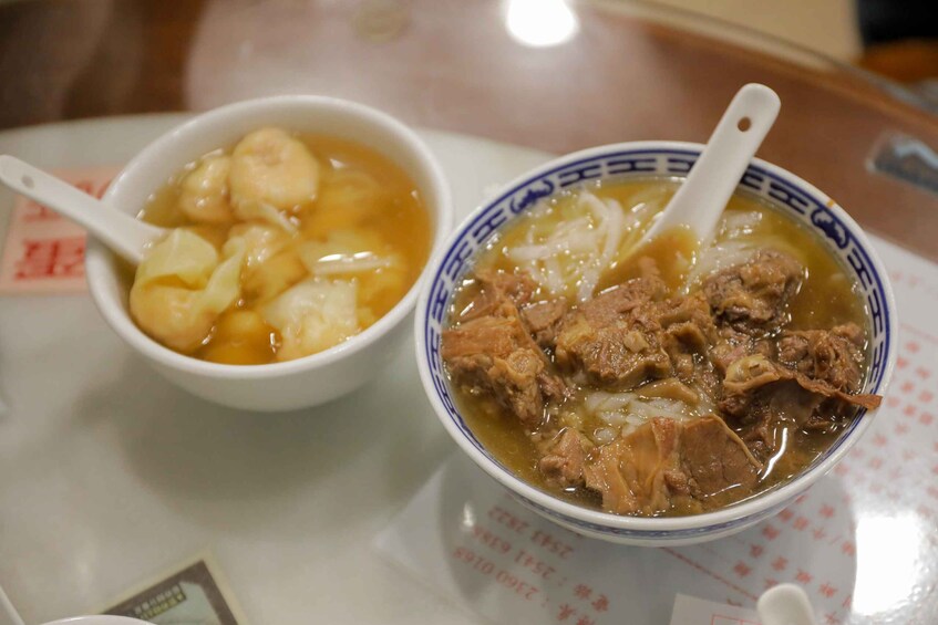 Two bowls of soup, one with dumplings and the other with meat, on a table. 4