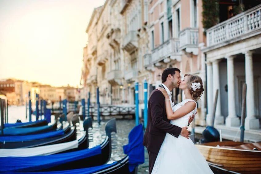 A couple embracing in a gondola-filled canal with historic buildings in the background. 5