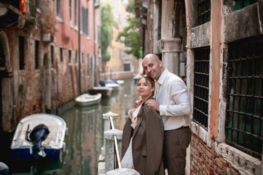 A narrow canal with boats, historic buildings, and a couple embracing. 4