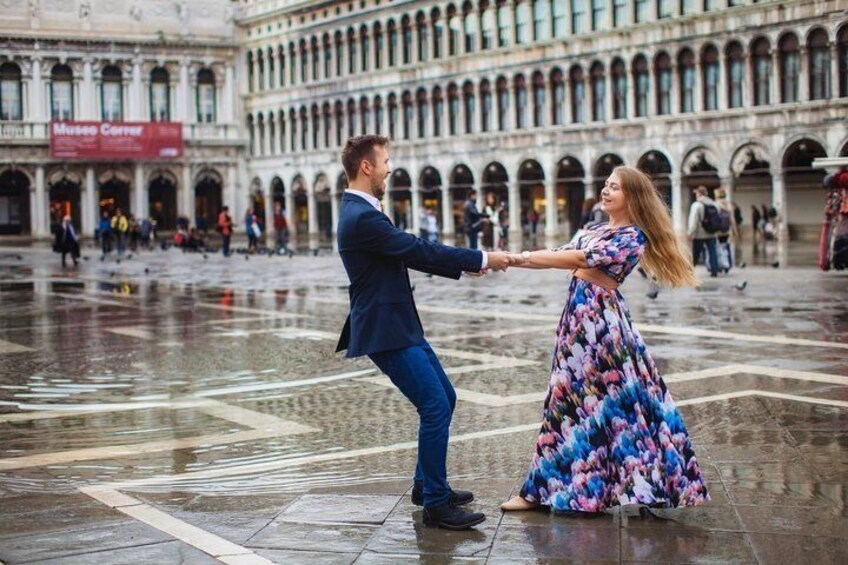 A couple dancing in a historic square with arches and a museum in the background. 3
