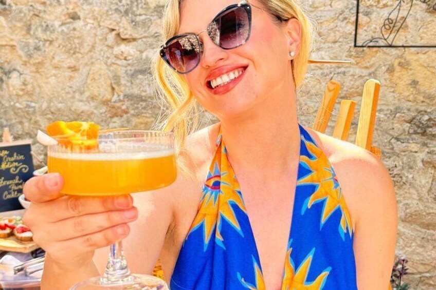 A person holding a cocktail glass with a slice of orange. 2