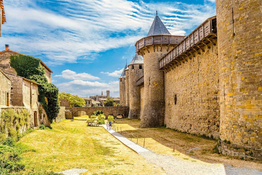 A medieval castle with a moat, stone walls, and a paved walkway. 4