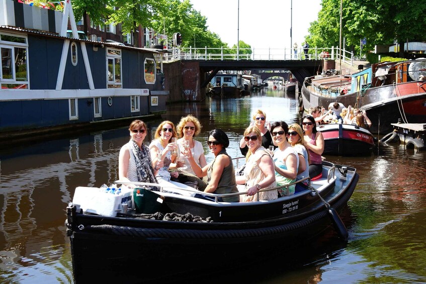 A group of people on a narrowboat, with a canal and a bridge in the background. 1