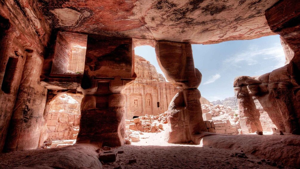 An ancient rock-cut tomb with large stone pillars and a central chamber. 2