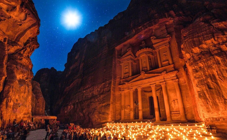 A rock-cut structure illuminated at night with a starry sky above. 3