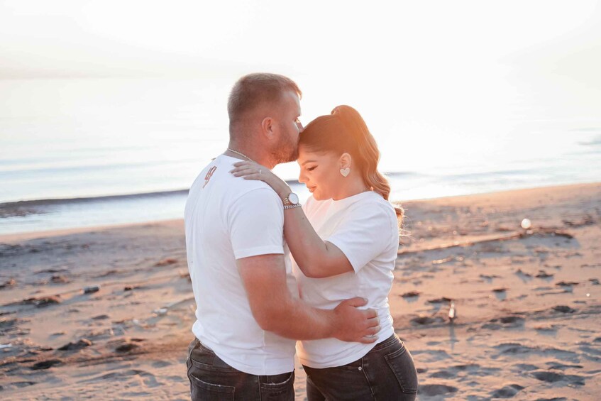 A couple embracing on a beach with the ocean in the background. 3