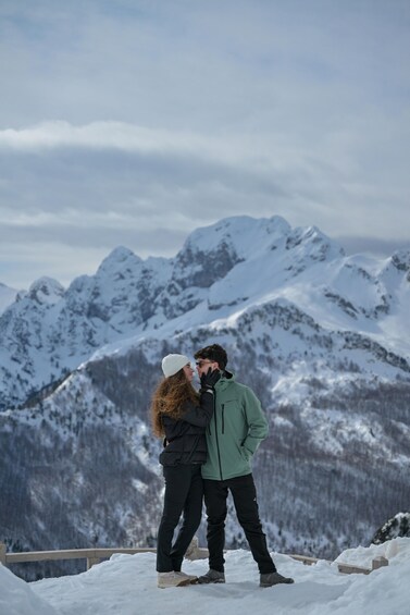 A couple embracing on a snowy mountain peak with snow-covered mountains in the background. 5