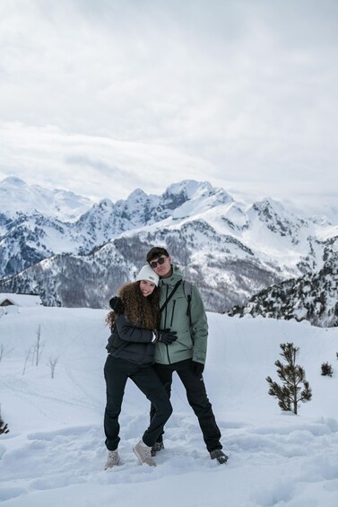 Two people embracing in a snowy mountainous landscape with snow-covered peaks in the background. 4
