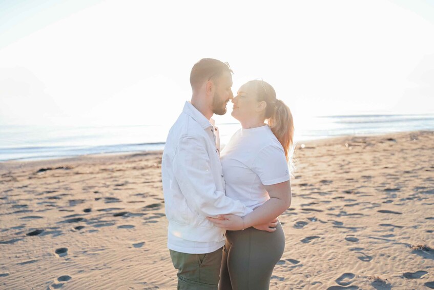A couple embracing on a sandy beach with the ocean in the background. 1