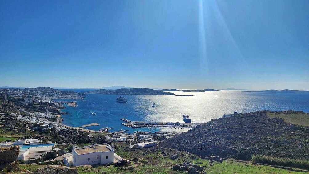 A coastal town with boats, a clear sky, and distant mountains. 5