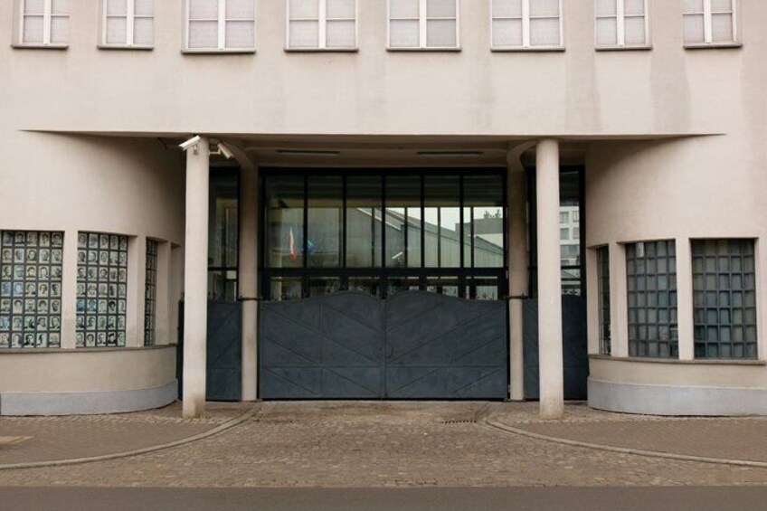 A building with a large entrance, a covered area with a patterned floor, and a series of windows on the side. 1