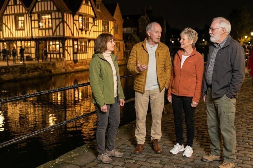 A group of people standing by a canal with traditional buildings in the background. 5