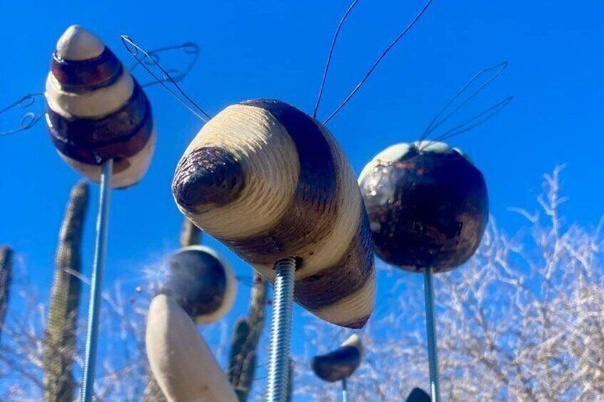 A sculpture of a bird with a metallic head and wooden body, set against a clear blue sky. 3