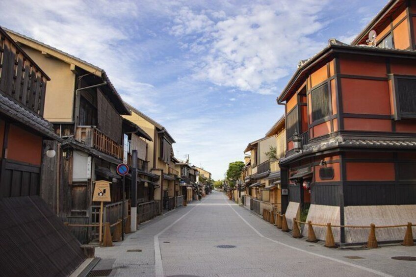 A narrow street lined with traditional wooden buildings, a no parking sign, and a clear sky. 5