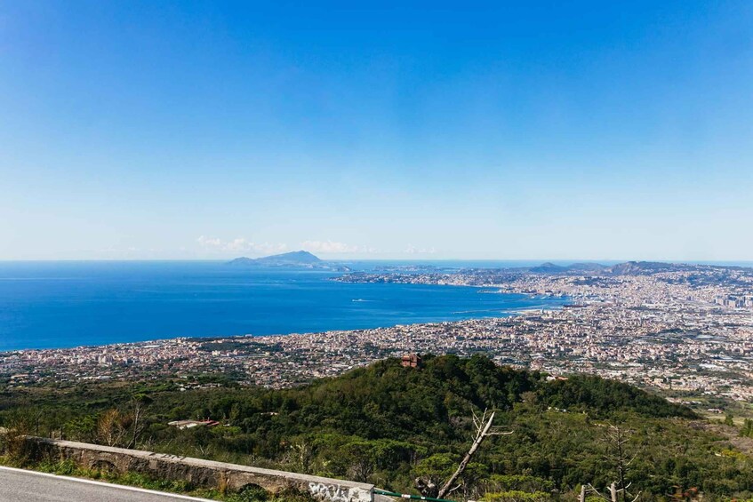 A coastal cityscape with a mountain in the distance, a clear blue sky, and a view of the sea. 2