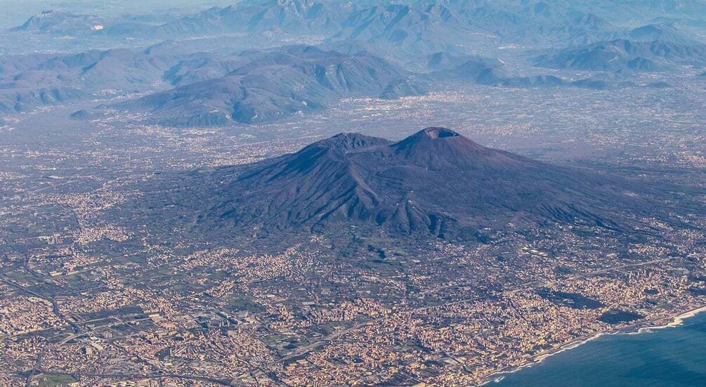 A cityscape with a prominent volcano in the background. 1