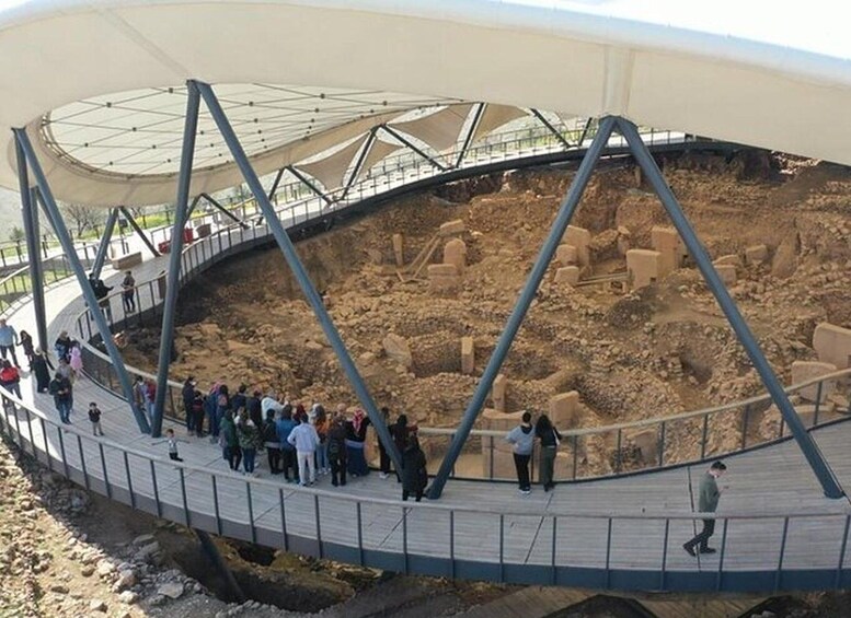 A museum with a large open excavation site, a walkway for visitors, and a covered roof structure. 2