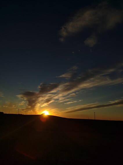 A sunset over a hilly landscape with a clear sky and a few clouds. 5