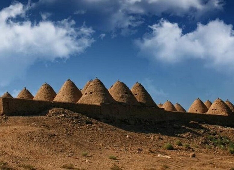 A series of conical structures on a hillside under a clear sky. 1