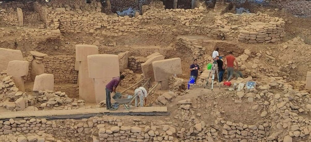 An archaeological site with exposed ruins and workers. 3