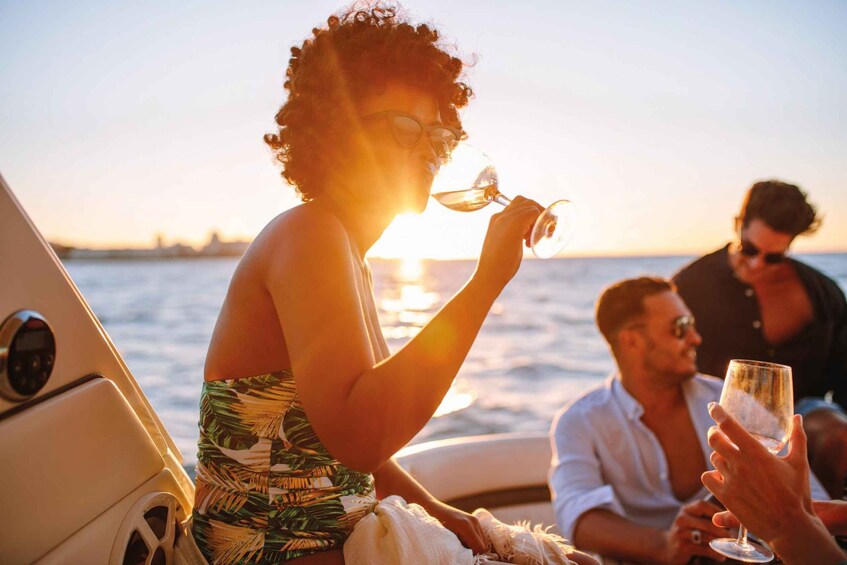A person holding a wine glass on a boat with the sun setting in the background. 4