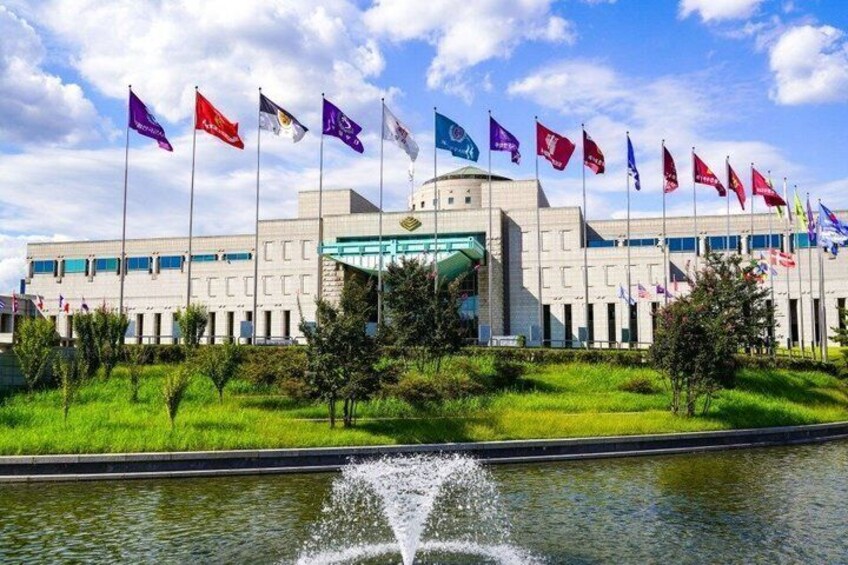 A building with multiple flags, a fountain, and a clear sky. 4