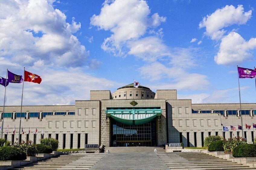 A large government building with a dome, multiple flags, and a green awning over the entrance. 1