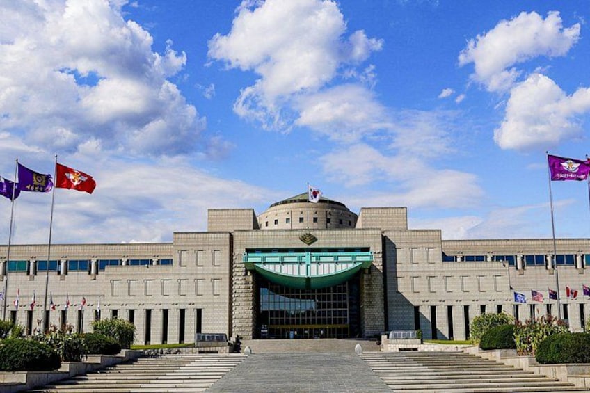A large government building with a dome, multiple flags, and a green awning. 1