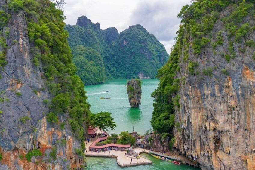 A karst landscape with limestone cliffs, a clear turquoise sea, and a small docked boat. 1