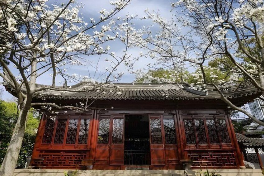 A traditional wooden structure with ornate windows and a tiled roof, surrounded by blooming cherry trees. 4