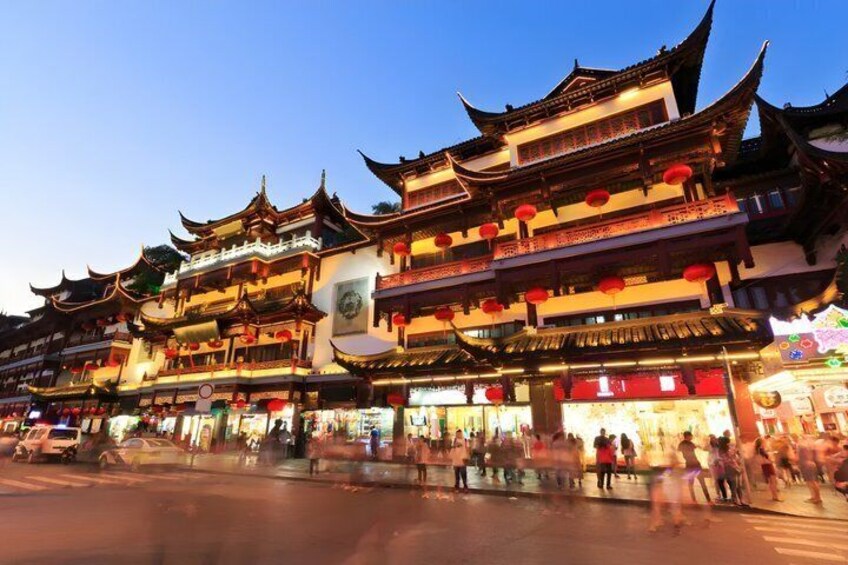 Traditional multi-tiered buildings with red lanterns, a street with pedestrians, and a clear sky. 3