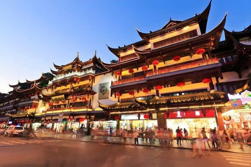 Traditional multi-tiered buildings with red lanterns, a street with pedestrians, and a clear sky. 3