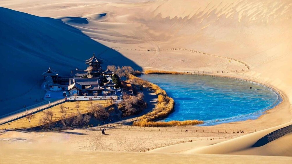 A traditional pagoda-style building by a river in a desert landscape. 3