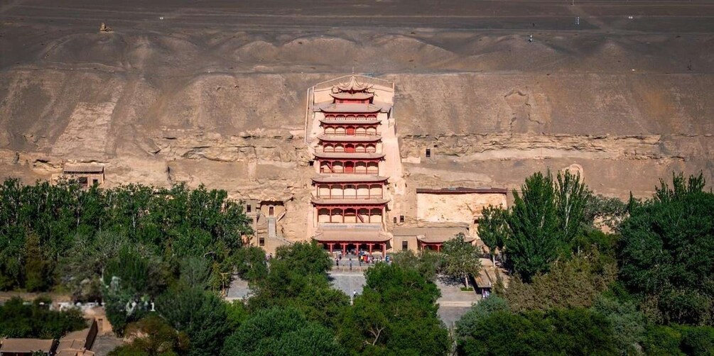 A multi-tiered pagoda with traditional architecture, surrounded by lush greenery and set against a barren landscape. 1