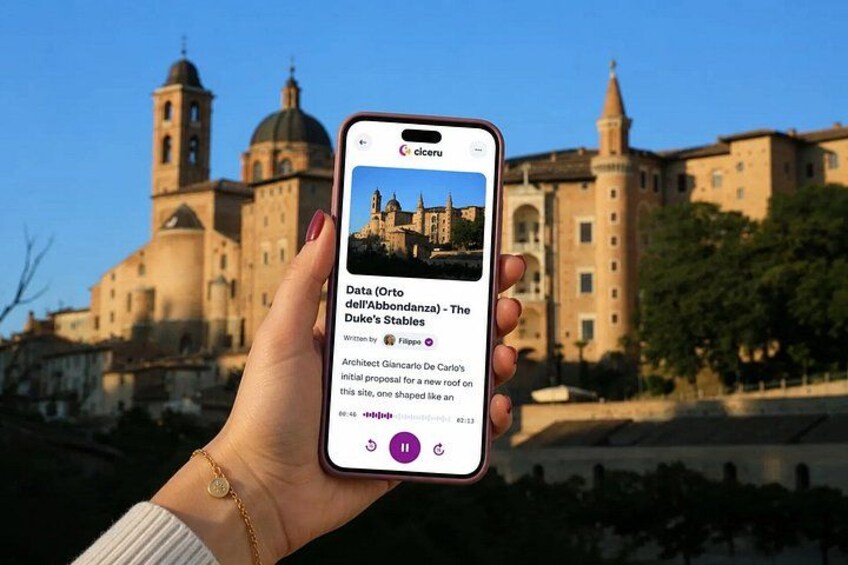 A hand holding a smartphone displaying a photo of a historic building with domes and towers, possibly a cathedral, with a clear sky in the background. 1