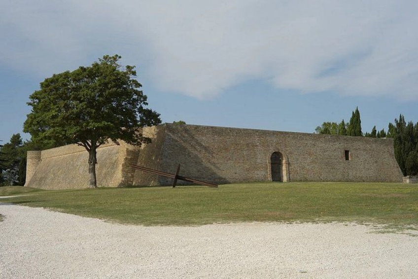 A large stone building with a tree in front, a gravel path, and a clear sky. 5
