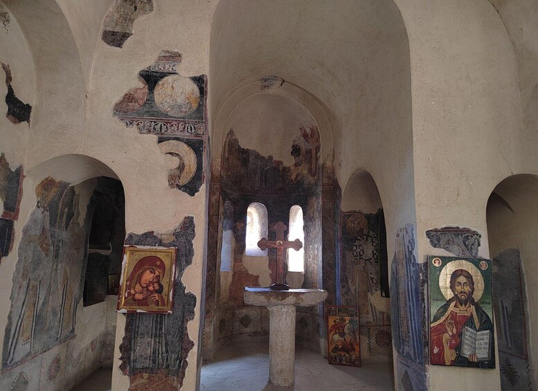 An ancient church interior with arched ceilings, frescoes, and religious icons. 1