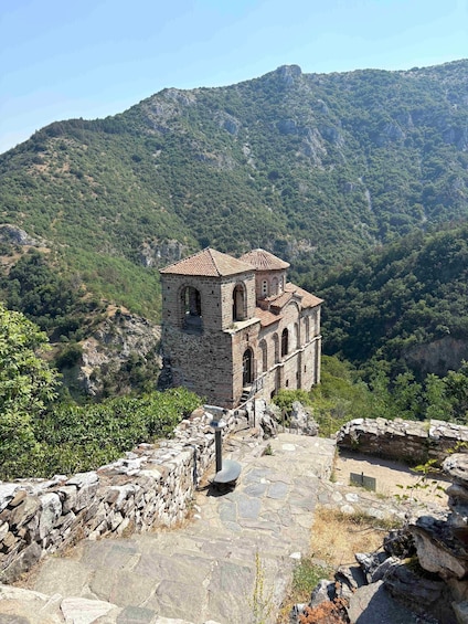 A stone church with a tiled roof, surrounded by a mountainous landscape. 5