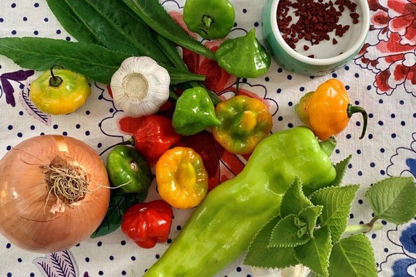 A variety of vegetables including onions, bell peppers, and garlic on a cloth with a floral pattern. 1