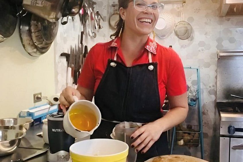 A person in a red shirt and apron pouring a liquid into a yellow bowl. 2