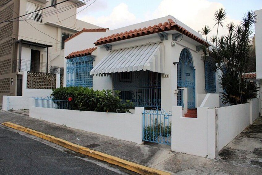 A white house with blue shutters, a tiled roof, and a gated entrance. 3