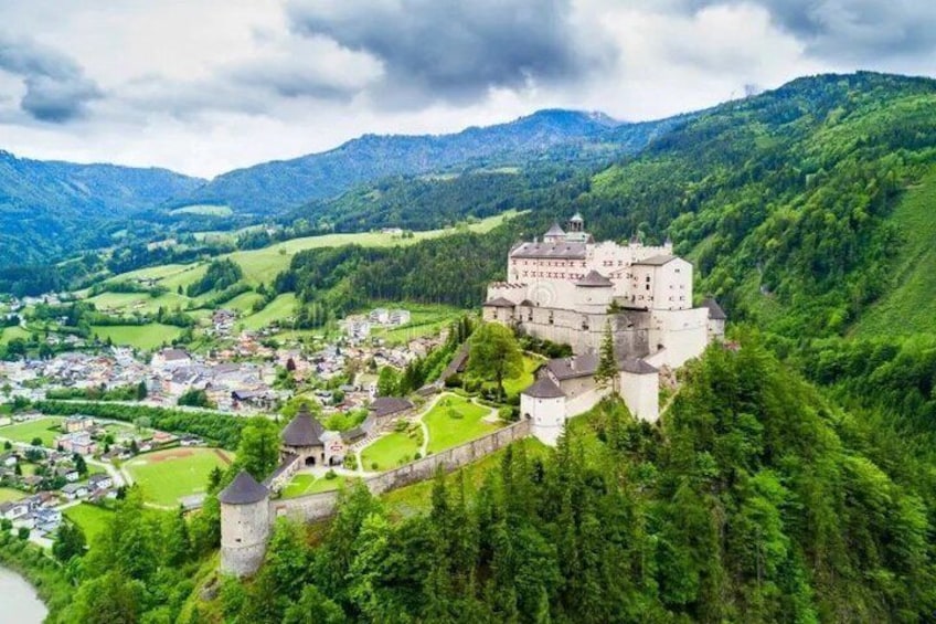 A castle on a hill overlooking a town surrounded by lush green hills. 5